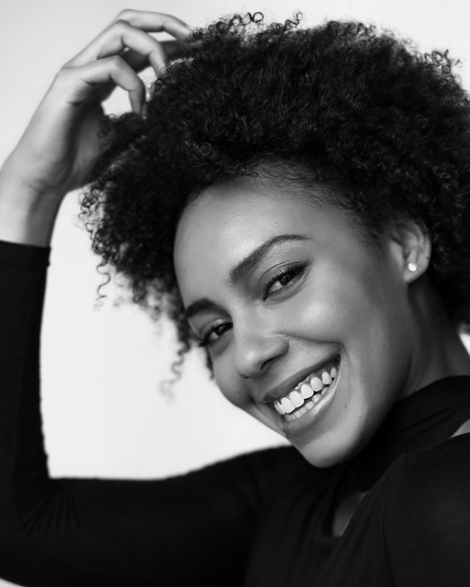Smiling woman with curly hair in a black and white portrait